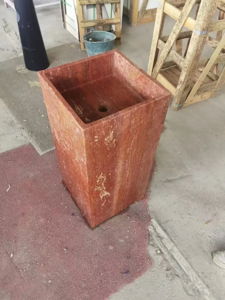 rose-red stone landscape feature, with a stone planter and linear travertine grain, in a workshop