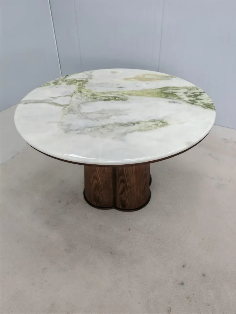 white stone coffee table, with a round top and bold veining, against a pale background