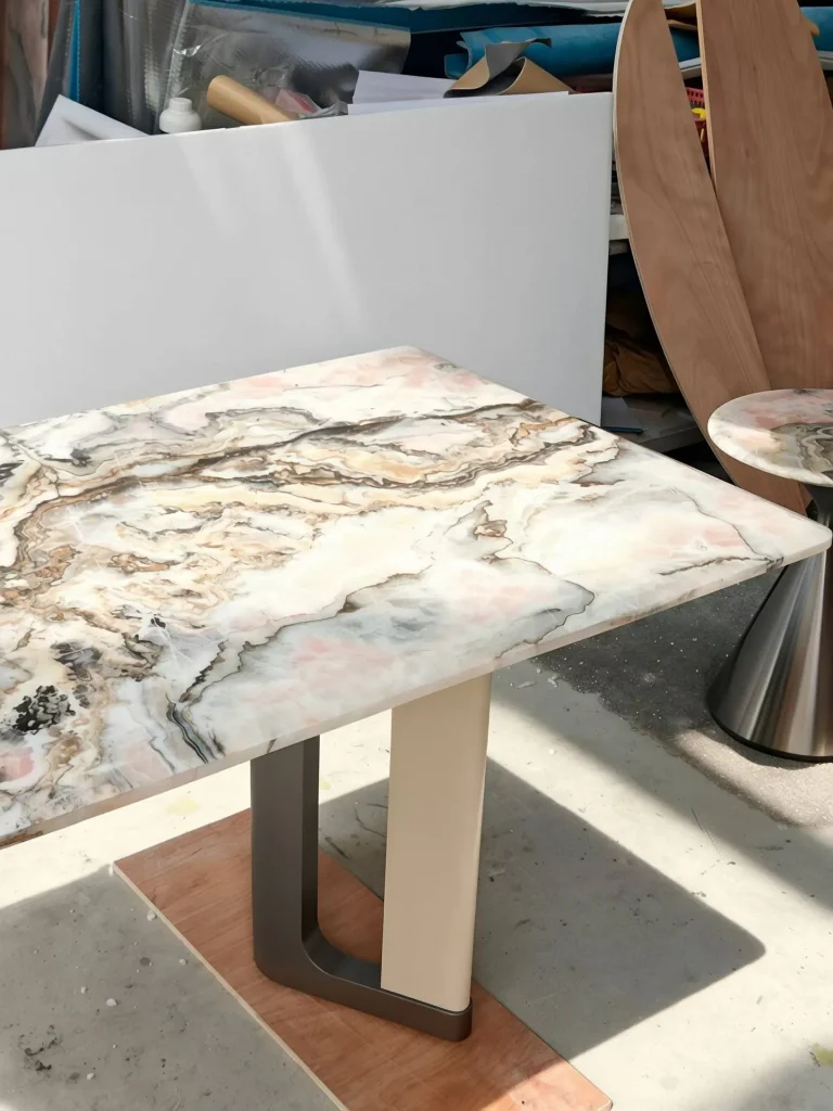 white stone dining table, with bold veining and a reflective finish, in a workshop