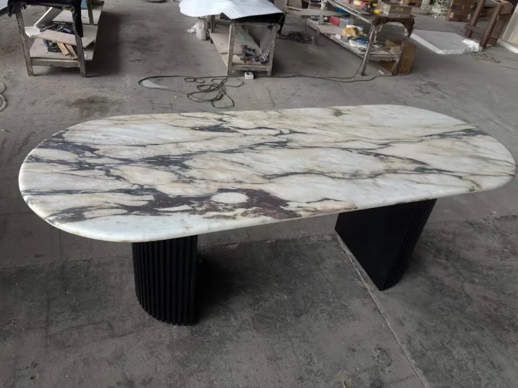 white stone dining table, with twin supporting bases and bold veining, in a workshop