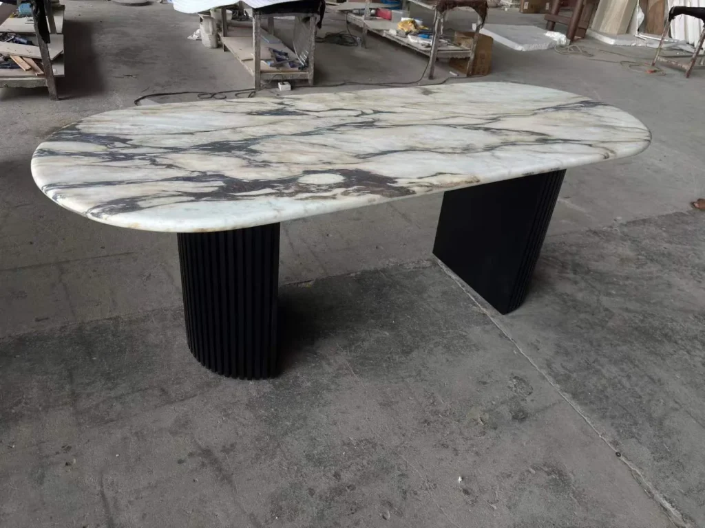 white stone dining table, with bold veining and workshop equipment nearby