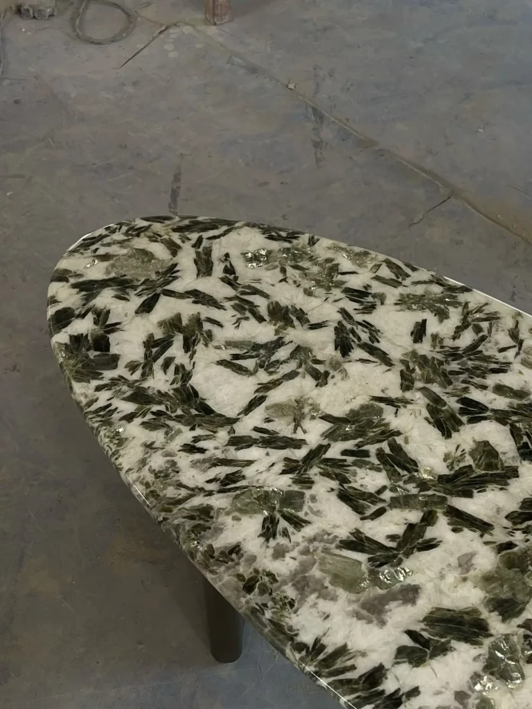 white stone coffee table, with an oval top and angular breccia fragments, in a workshop