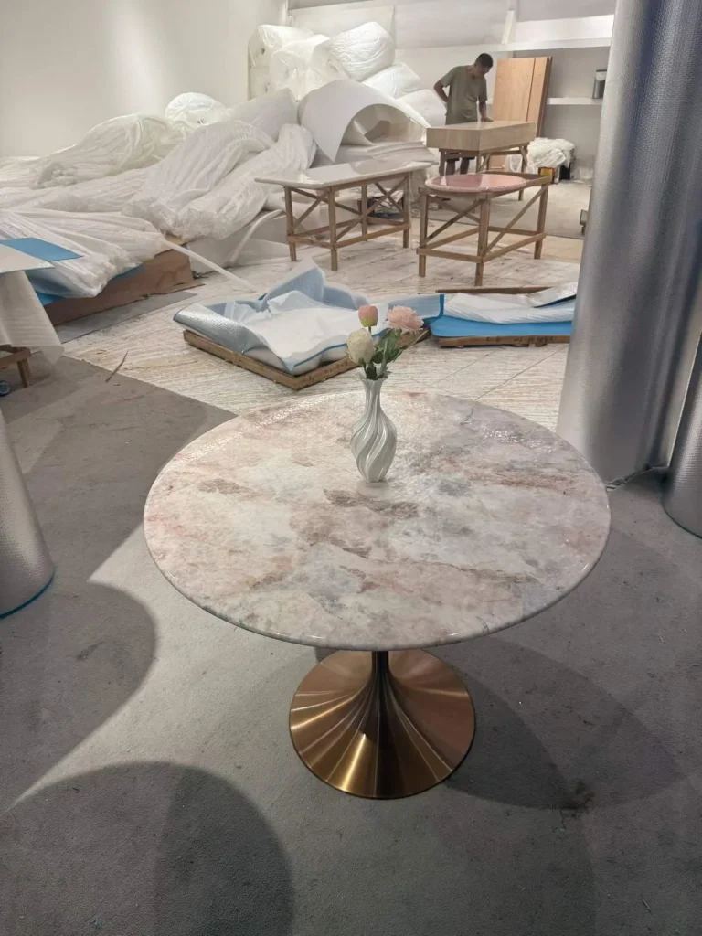 white stone coffee table, with a round top and cloudy mottling, in a workshop