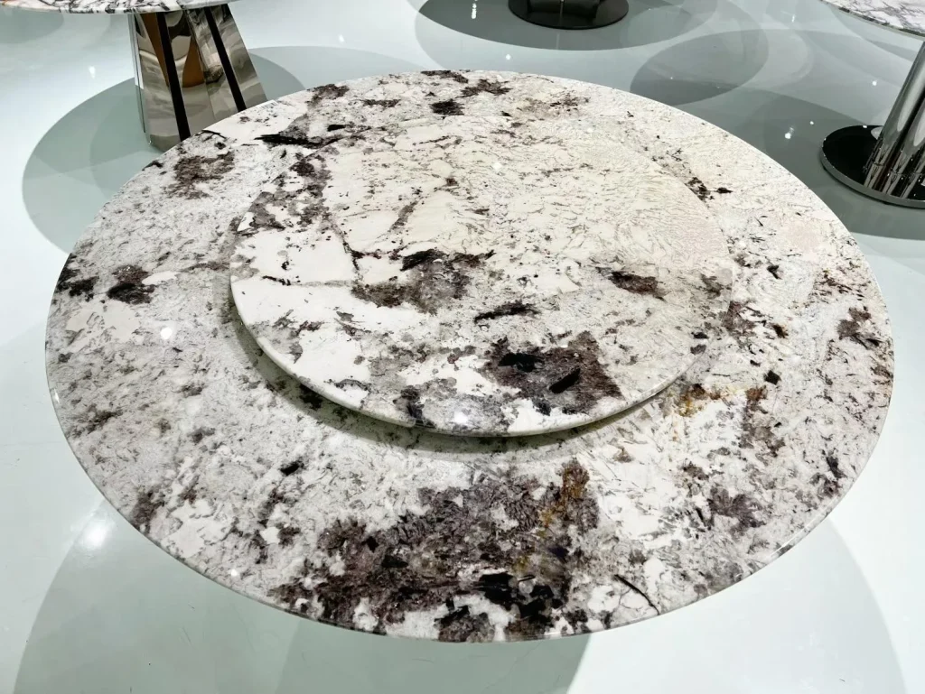 white stone dining table, with a round top and cloudy mottling, in a showroom