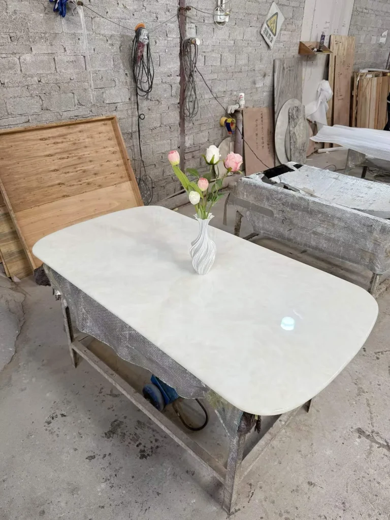 white stone dining table, with cloudy mottling and a reflective finish, in a workshop