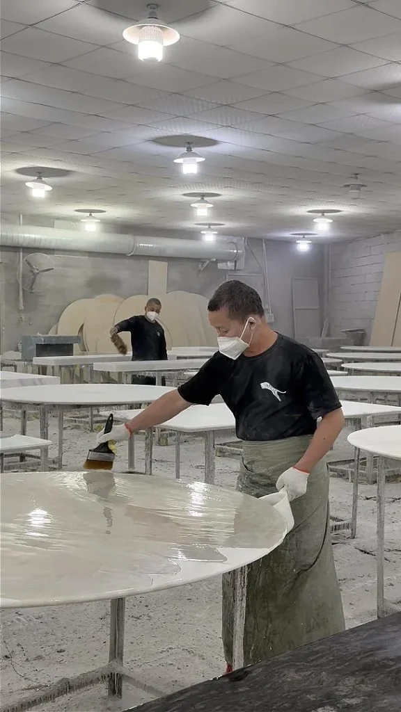 white stone dining table, with a round top and cloudy mottling, in a workshop