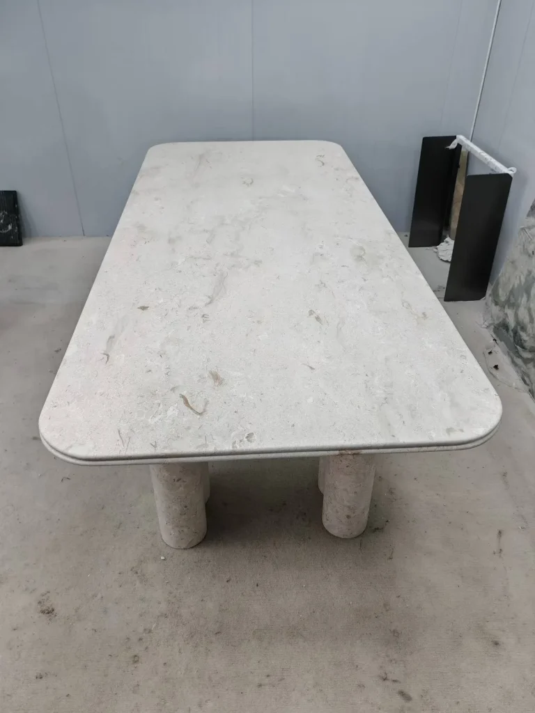 white stone dining table, with fine veining, in a workshop