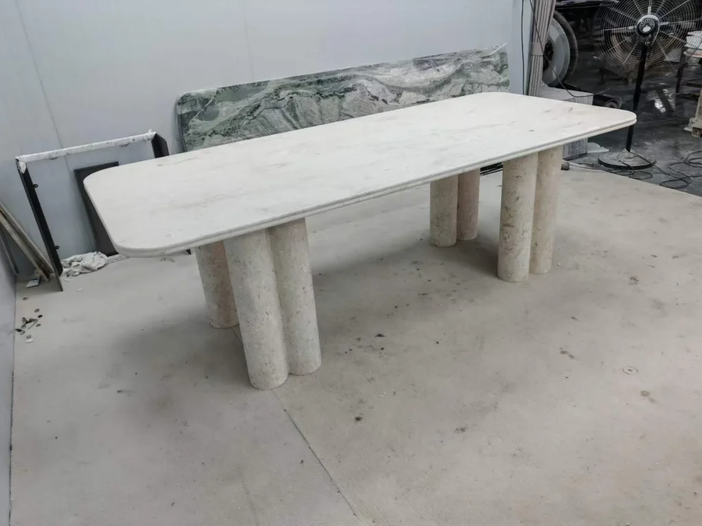white stone dining table, with twin supporting bases and fine veining, in a workshop