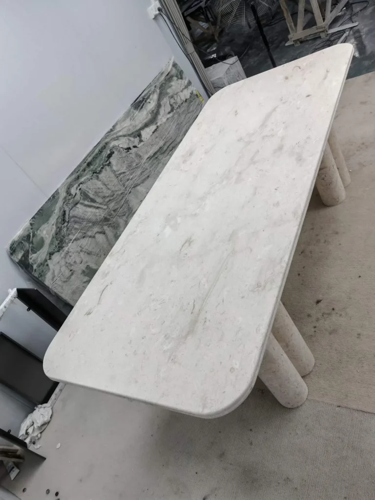 white stone dining table, with twin supporting bases and fine veining, in a workshop