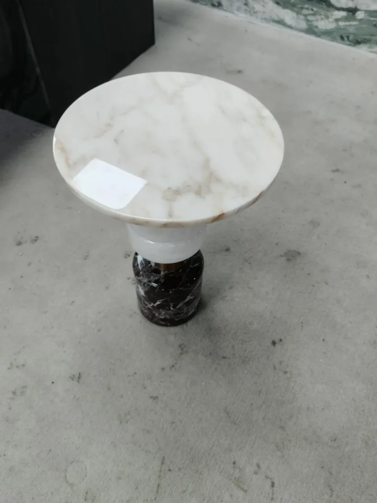 white stone side table, with a round top and fine veining, in a showroom