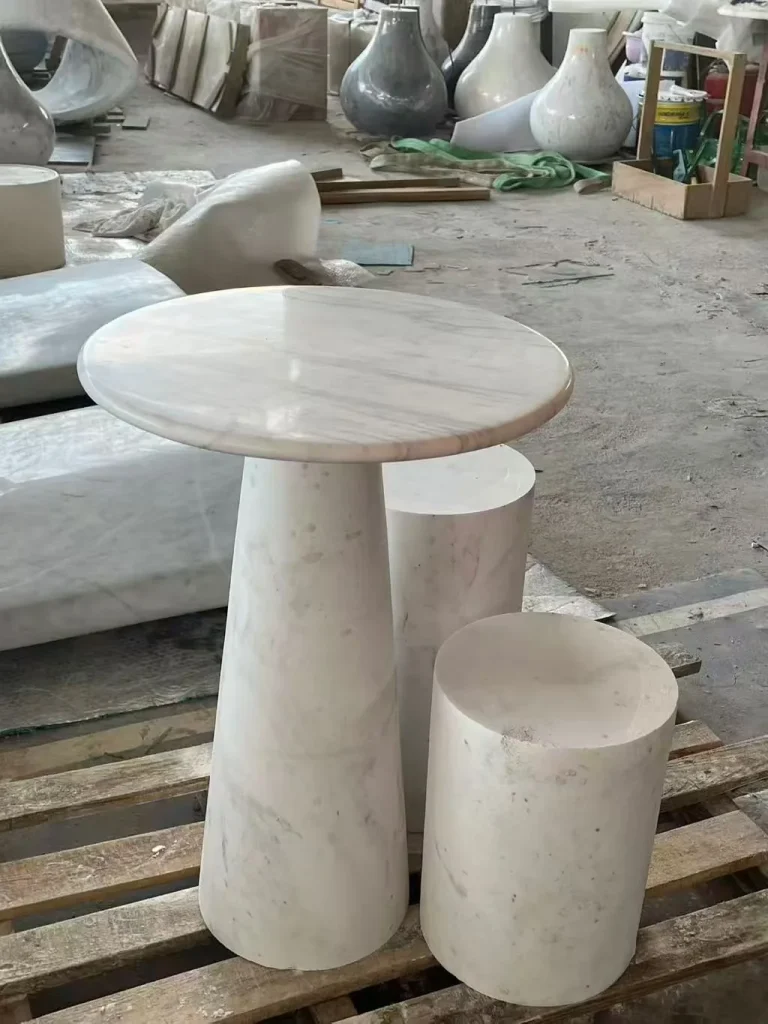 white stone side table, with a central pedestal base and fine veining, in a workshop