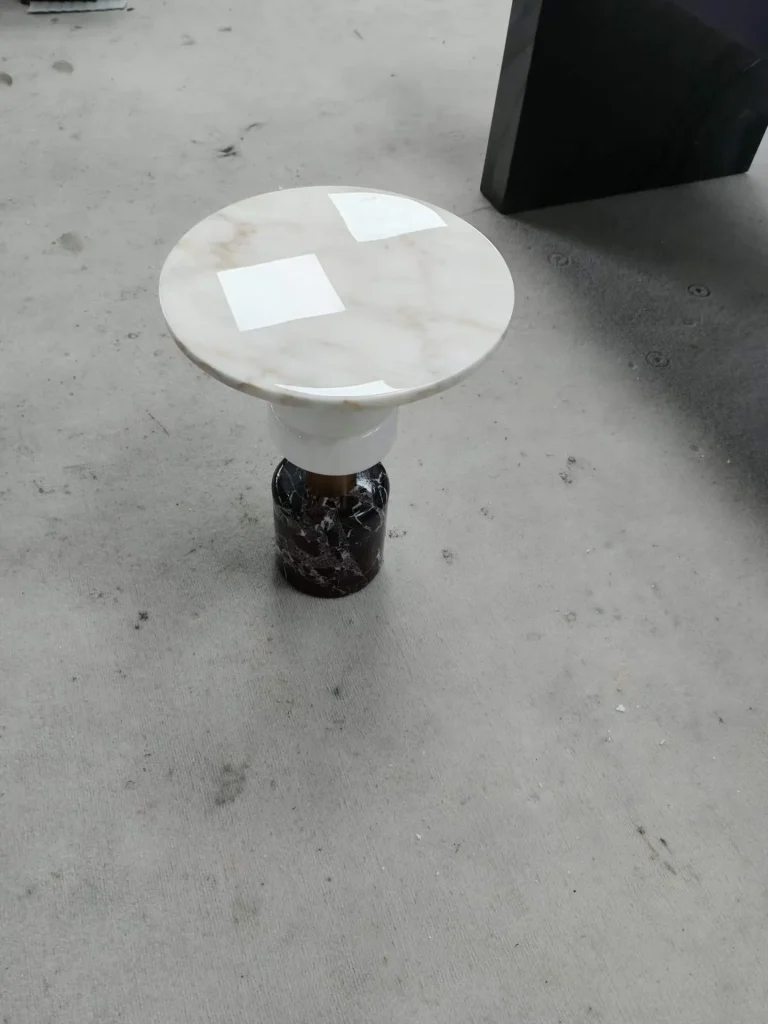 white stone side table, with a round top and fine veining, in a workshop