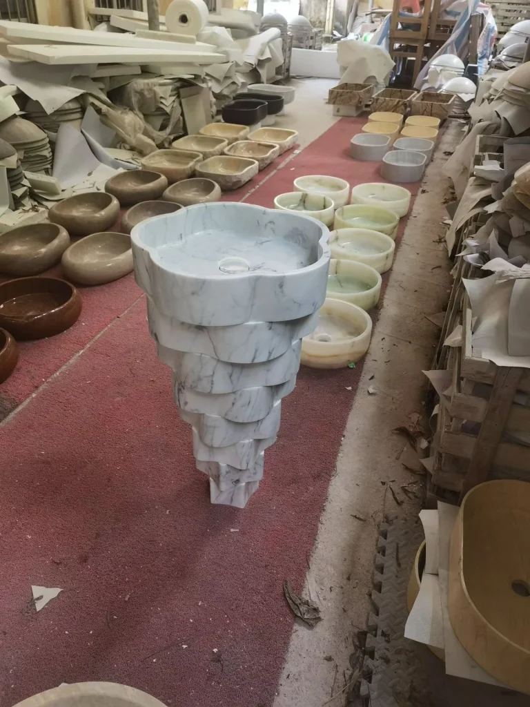 white stone sink, with a stone pedestal and fine veining, in a workshop